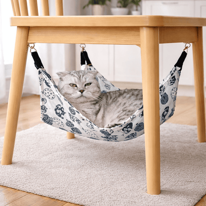Hamac à chat suspendu avec chat blanc confortablement installé sous une chaise