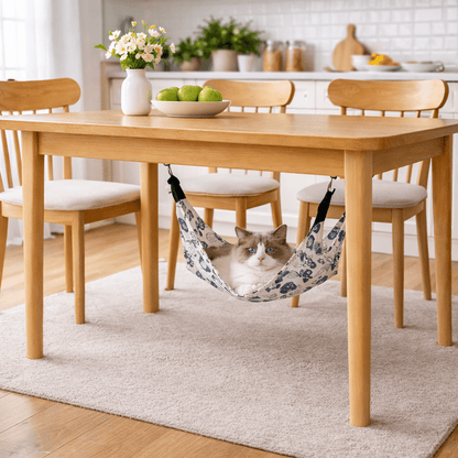 Hamac à chat suspendu installé sous une table en bois dans un intérieur lumineux