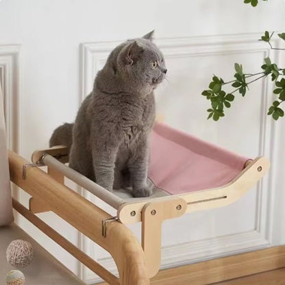 Gros chat gris assis dans un hamac pour chat rose